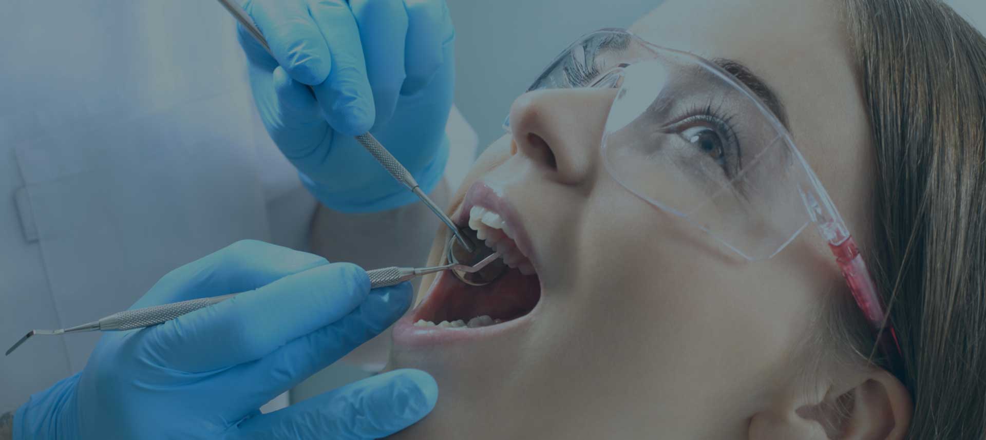 Paciente com boca aberta sendo examina por um dentista