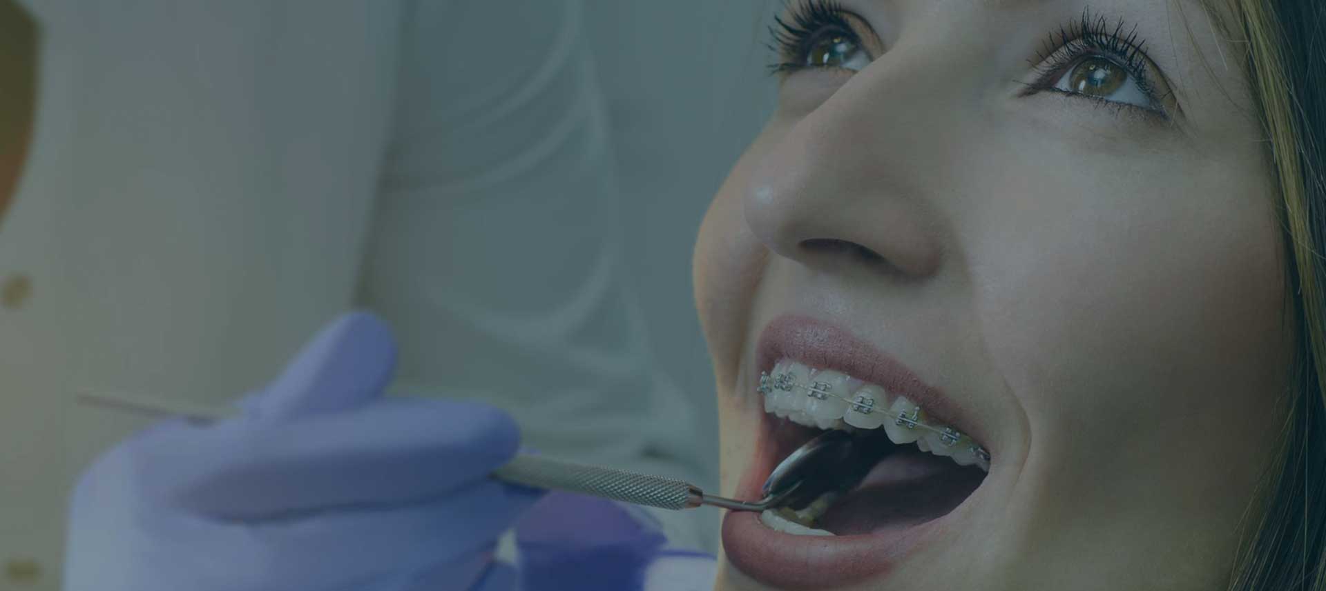 Mulher com aparelho dentário sendo examinada por um dentista